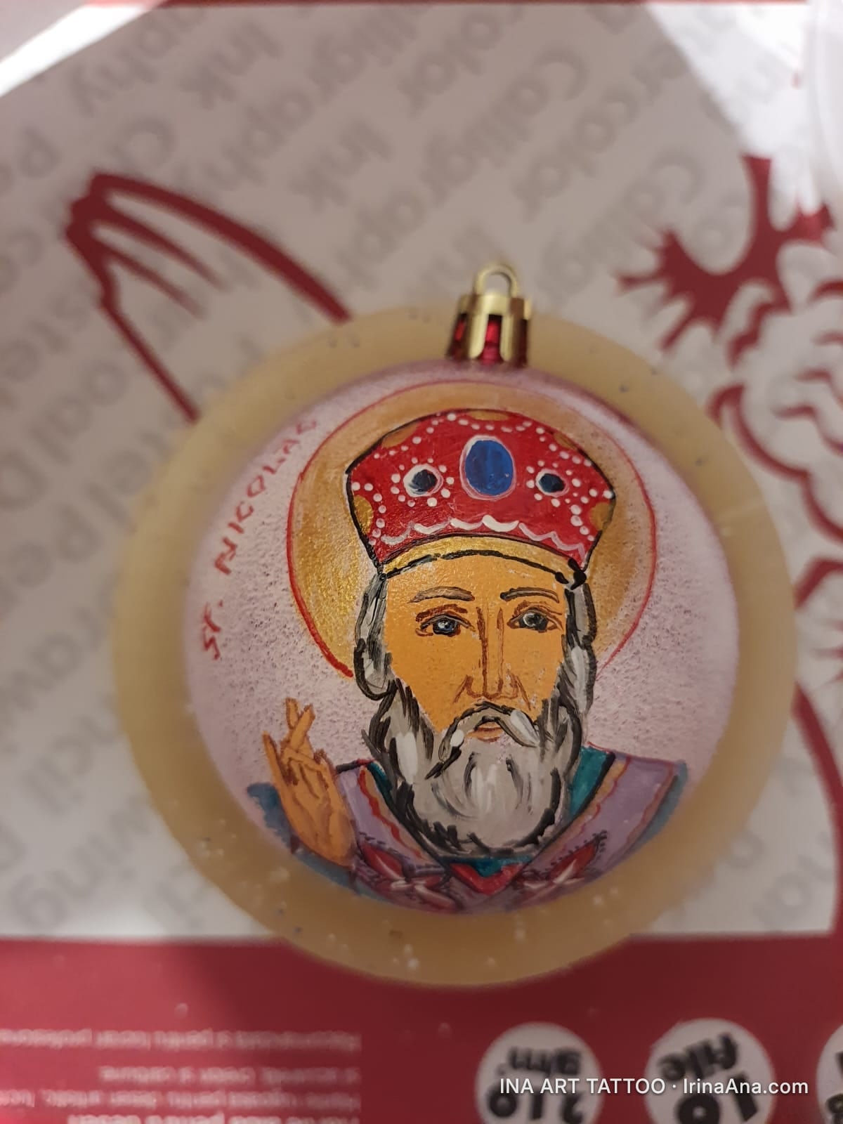 O pictură a Sfântului Nicolae pe un glob de Crăciun, cu o aură aurie și o coroană roșie cu pietre prețioase.