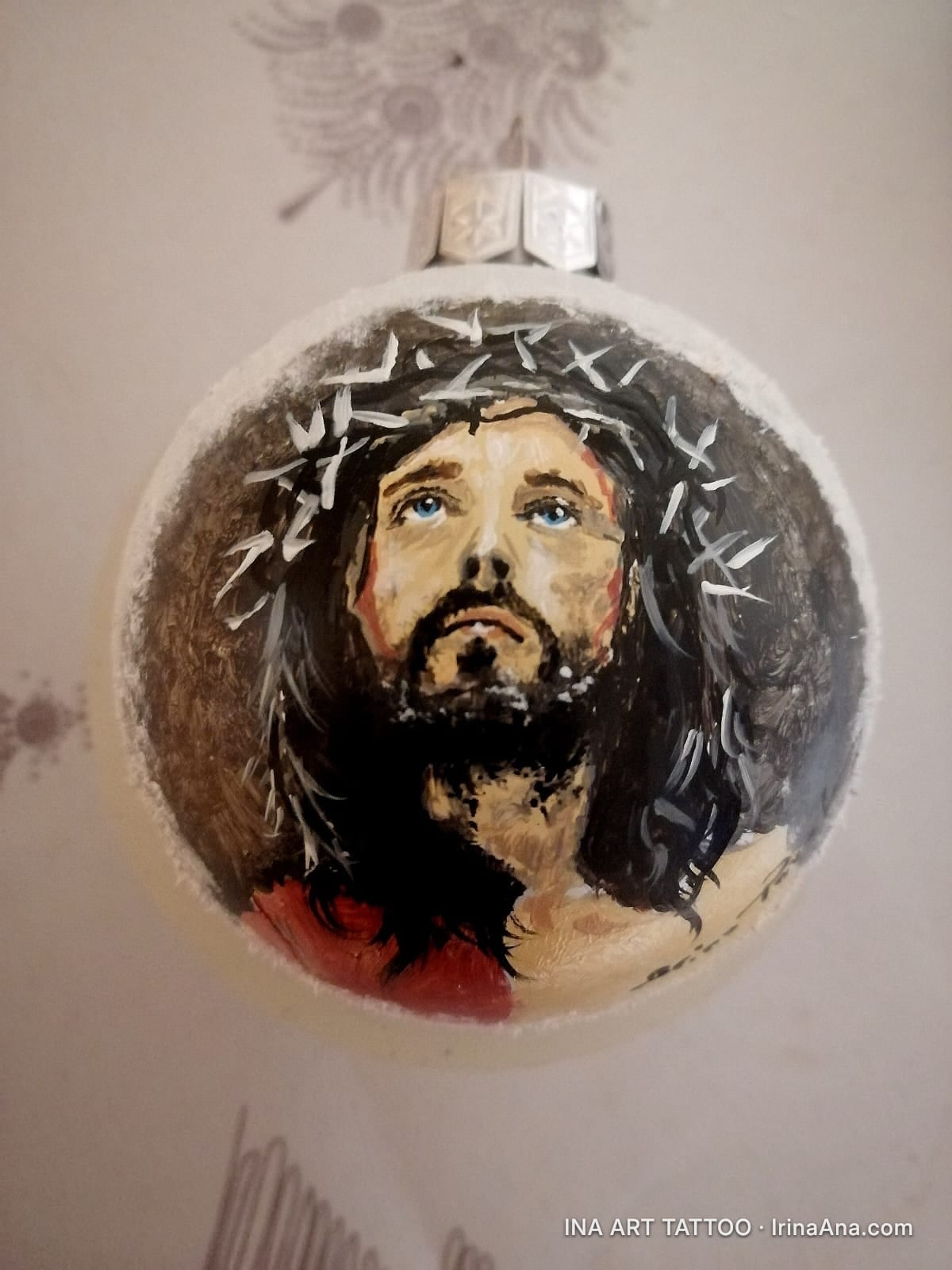Glob de Crăciun pictat manual, cu chipul lui Iisus Hristos purtând o coroană de spini. Culori închise, tonuri pământii.