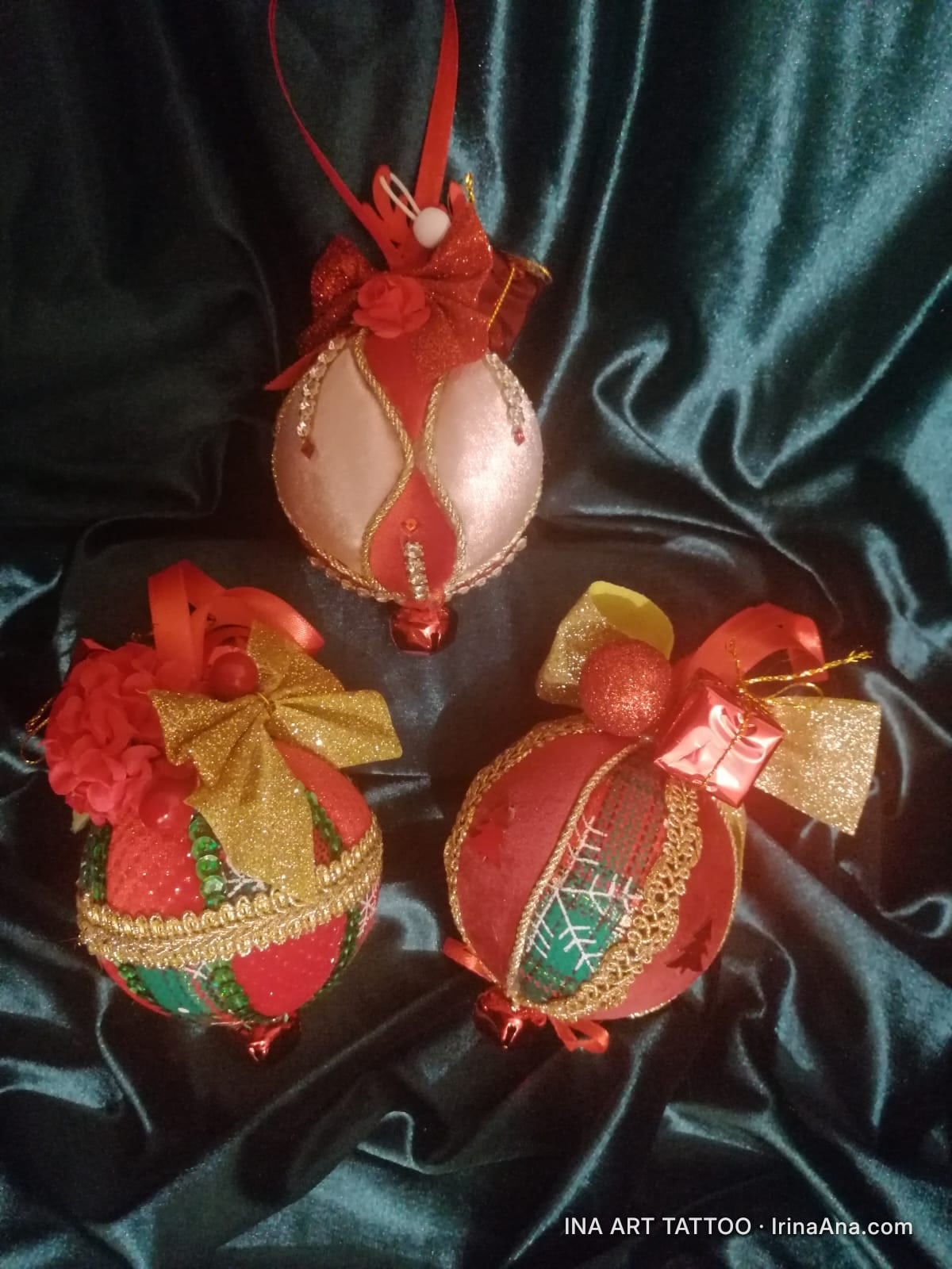 Trei ornamente de Crăciun lucrate manual, în nuanțe de roșu, auriu, verde și alb, decorate cu panglici și mărgele, așezate p…