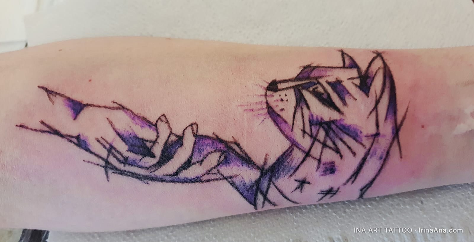Abstract tattoo on forearm with a stylized hand and cat, predominantly purple and black.