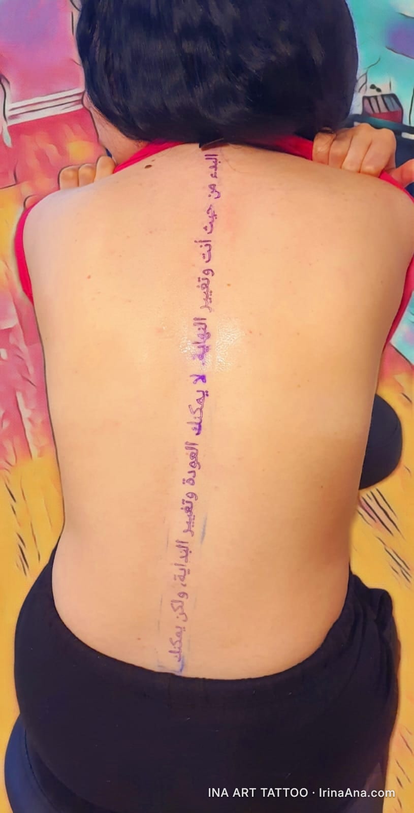 Vertical Arabic script tattoo on a person's spine, viewed from the back.