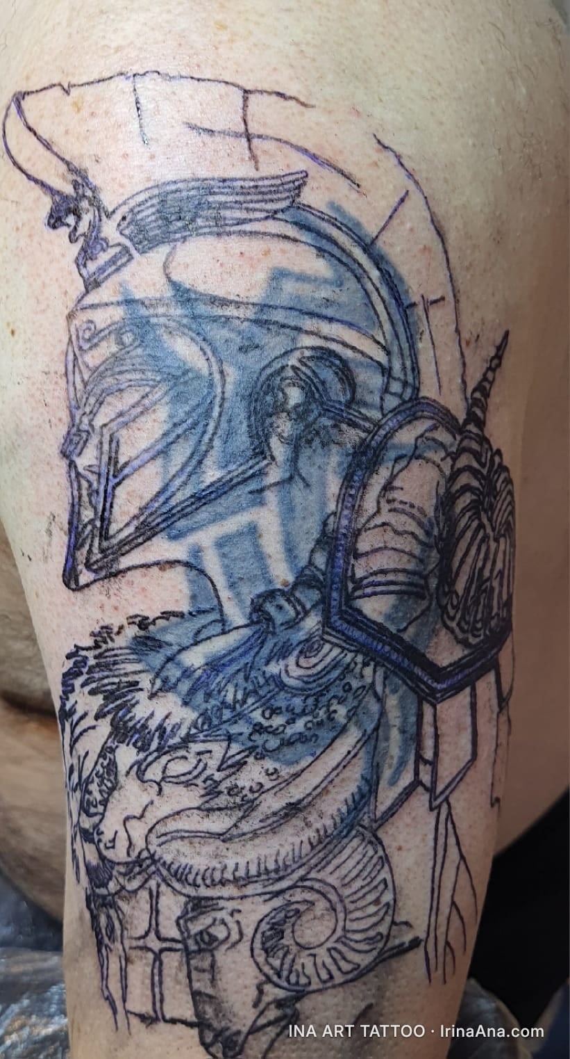 Outline of a tattoo on an arm, depicting a Spartan helmet and a ram, with visible blue transfer.