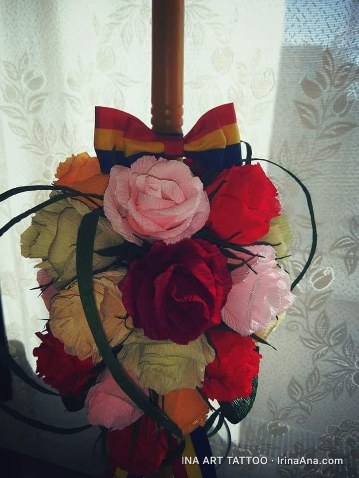 Wedding candle decorated with various colored crepe paper flowers and a tricolor bow.
