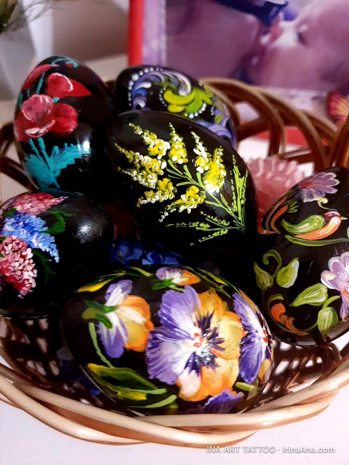 Basket with glossy black Easter eggs, hand-painted with colorful flowers in a traditional Romanian style.
