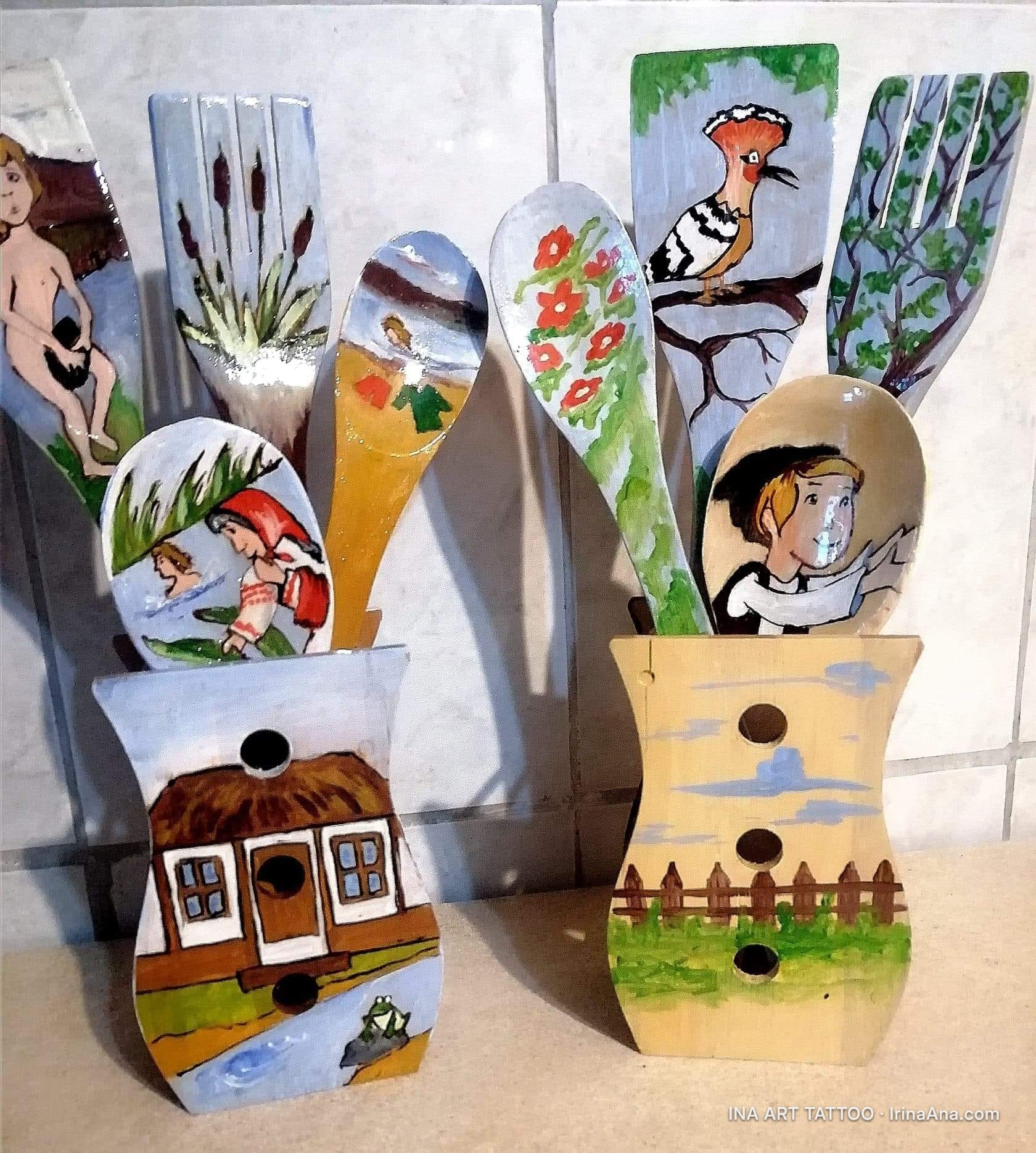 Two painted wooden holders with painted wooden spoons and kitchen utensils, in a folk art style.