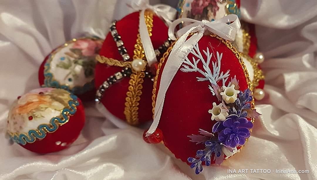 Three handmade Easter eggs, wrapped in red velvet and adorned with ribbons, pearls, and small flowers.