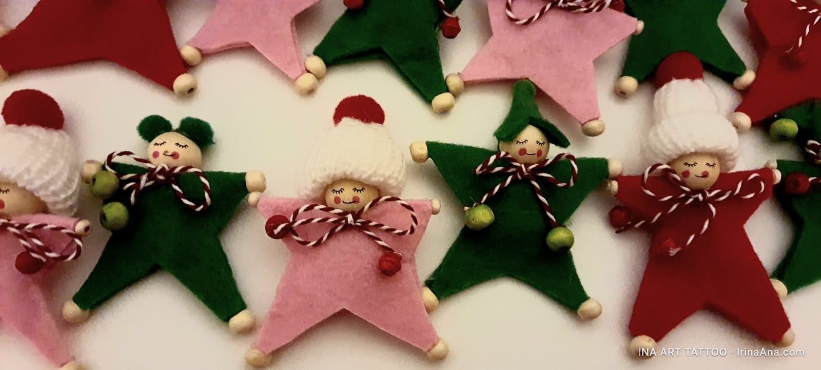 Star-shaped Mărțișor dolls made of red, pink, and green felt, with wooden heads and knitted hats.