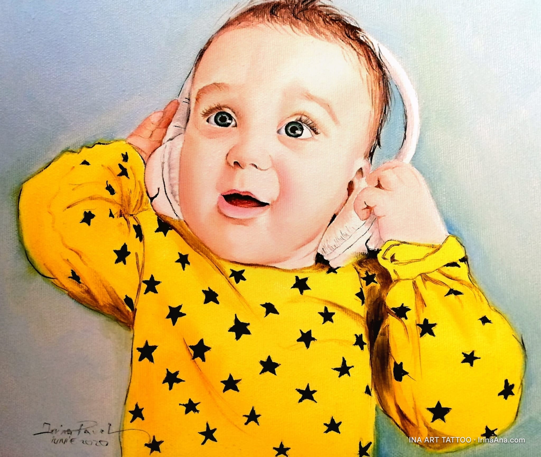 A baby with brown hair and blue eyes, wearing a yellow shirt with black stars and white headphones.