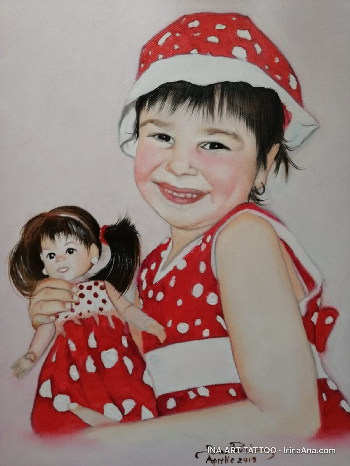 Portrait of a smiling girl in a red and white polka dot hat and dress, holding a matching doll.