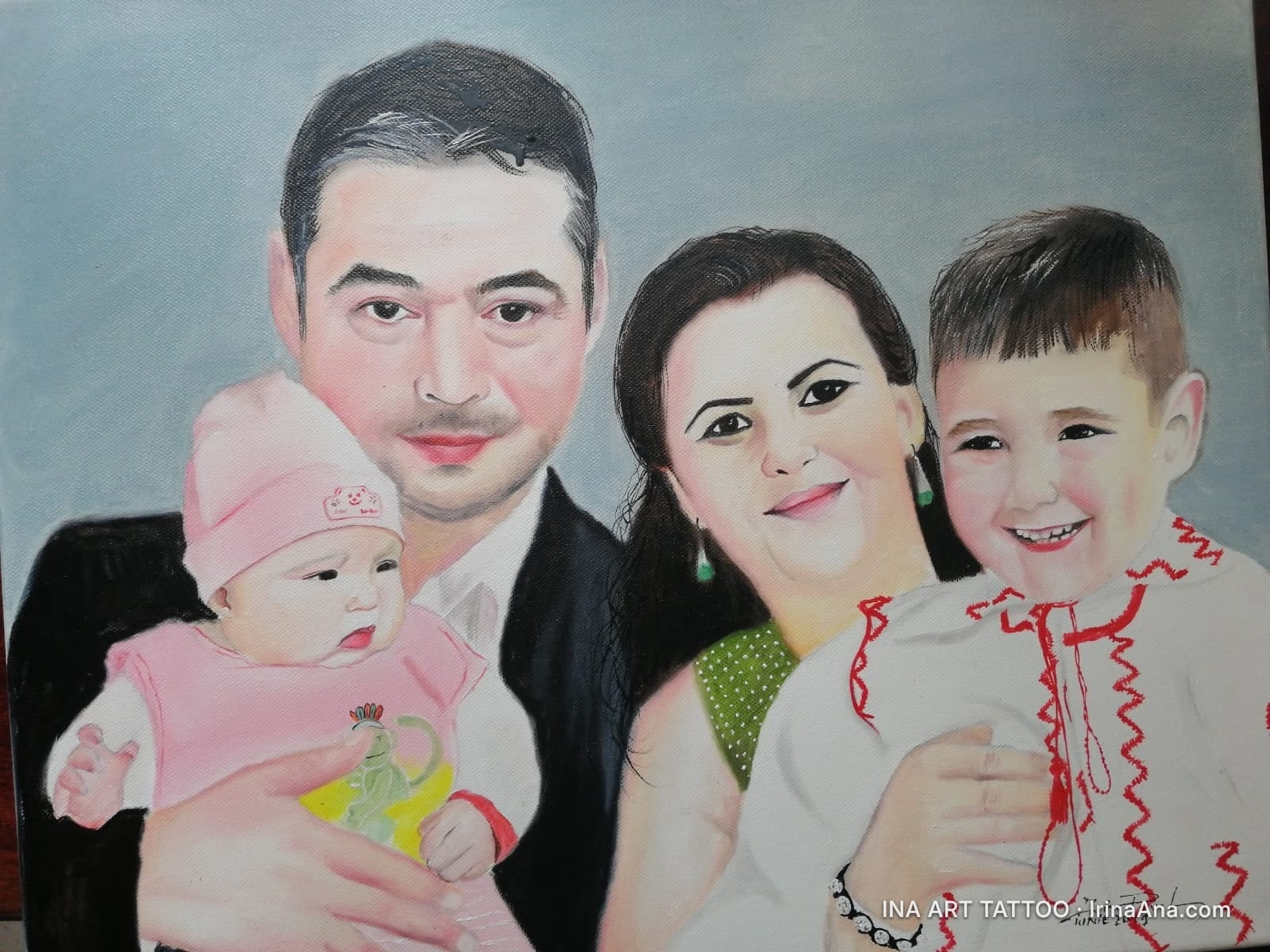 Family portrait: a man holds a baby, and a woman holds an older boy, all smiling.