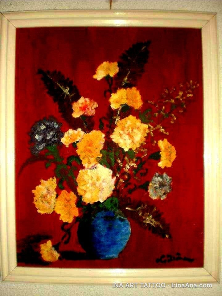 Oil painting of yellow and orange flowers in a blue vase, set against a dark red background. One flower has fallen next to t…