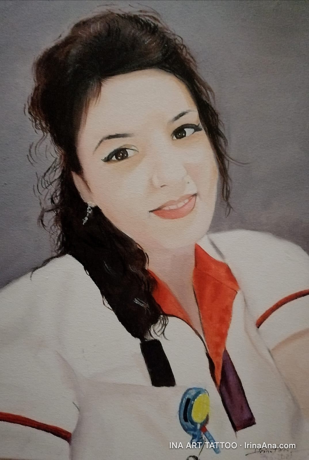 Portrait of a smiling young woman with dark brown hair, wearing a white uniform with an orange collar.