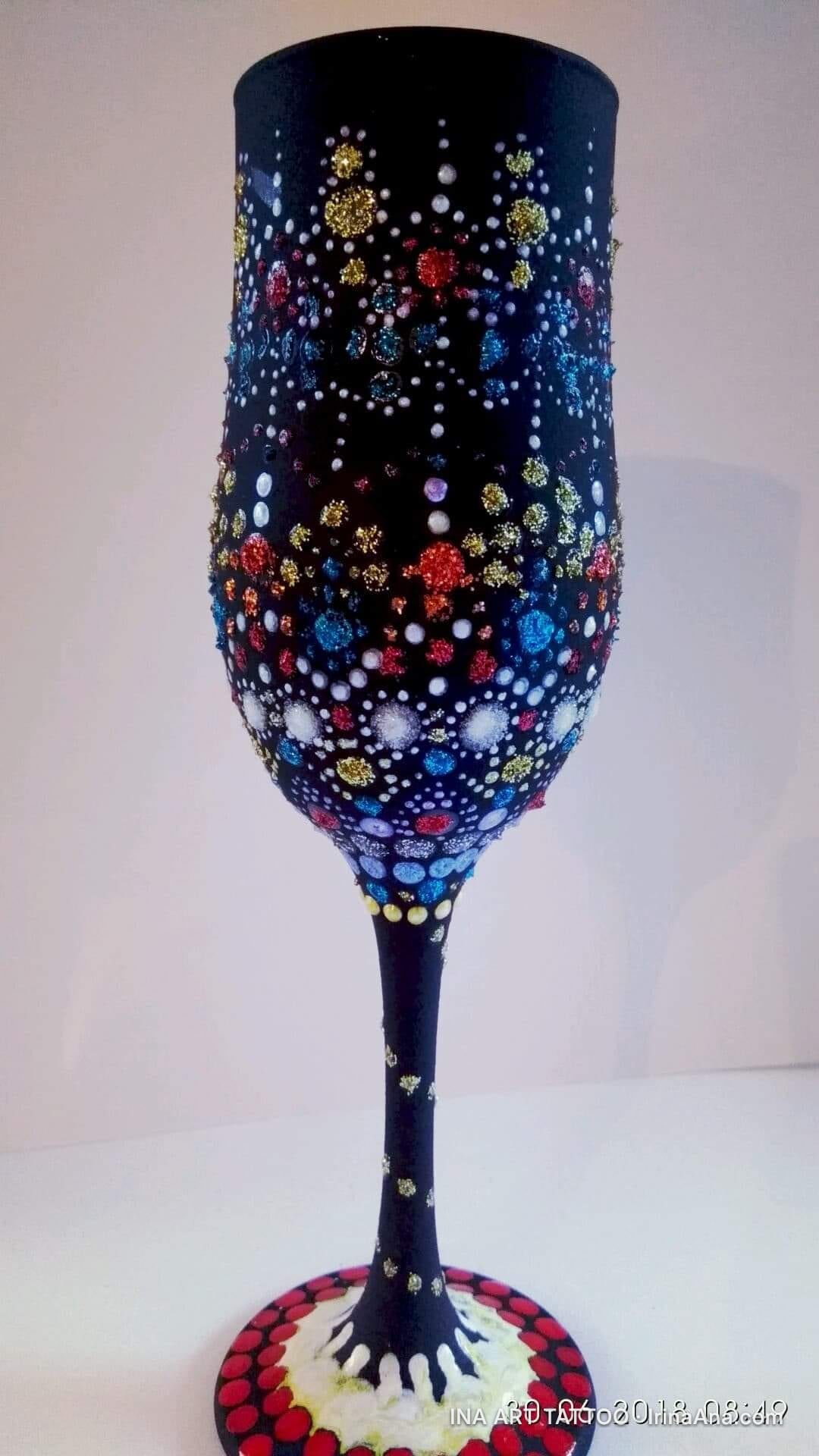 Pahar de șampanie negru, decorat cu puncte multicolore, de diferite mărimi, dispuse dens pe cupă și picior.