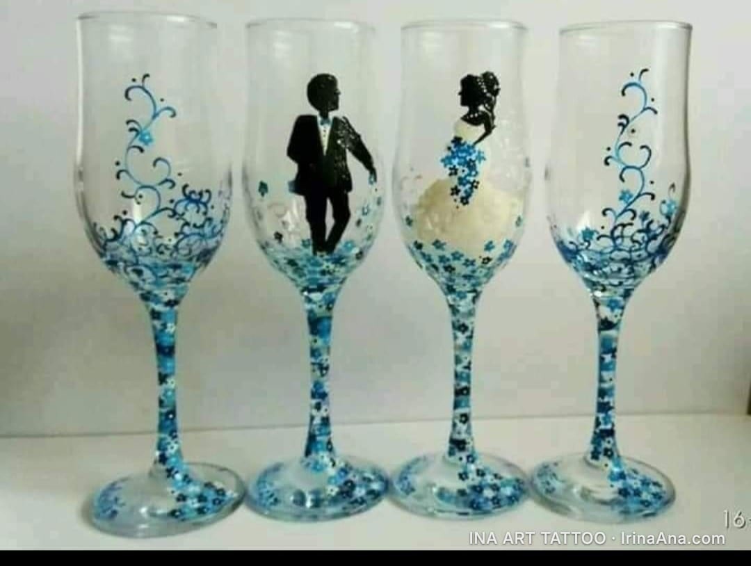 Patru pahare de șampanie din sticlă, decorate cu motive florale albastre și siluete de mire și mireasă.