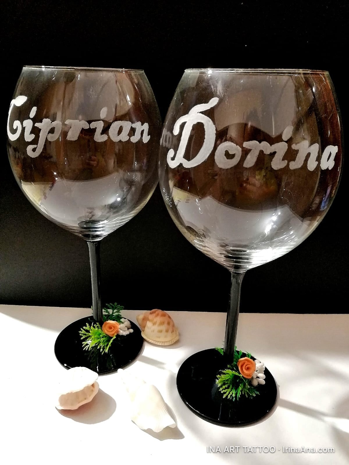 Două pahare de vin personalizate cu numele Ciprian și Dorina, decorate cu flori mici și scoici la bază.