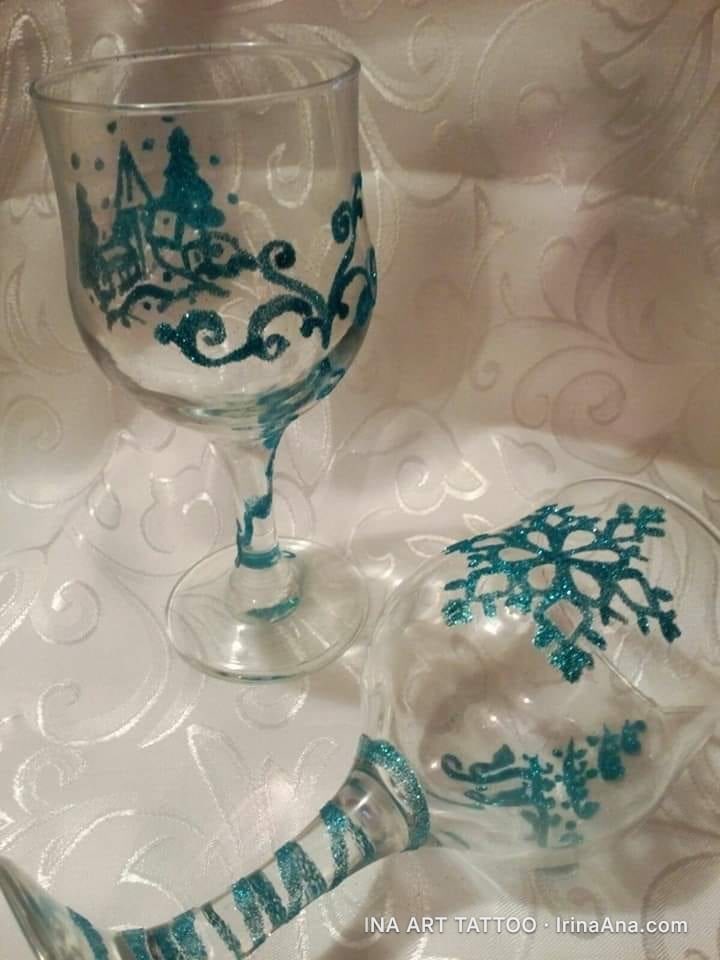 Două pahare de vin și un glob de sticlă, decorate cu modele de iarnă în sclipici albastru-verzui.