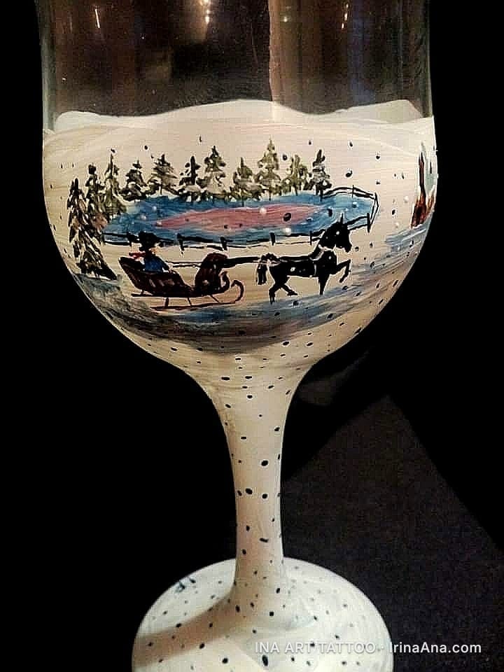 Pahar de vin pictat manual cu o scenă de iarnă: o sanie trasă de un cal pe un lac înghețat, înconjurat de brazi și zăpadă.