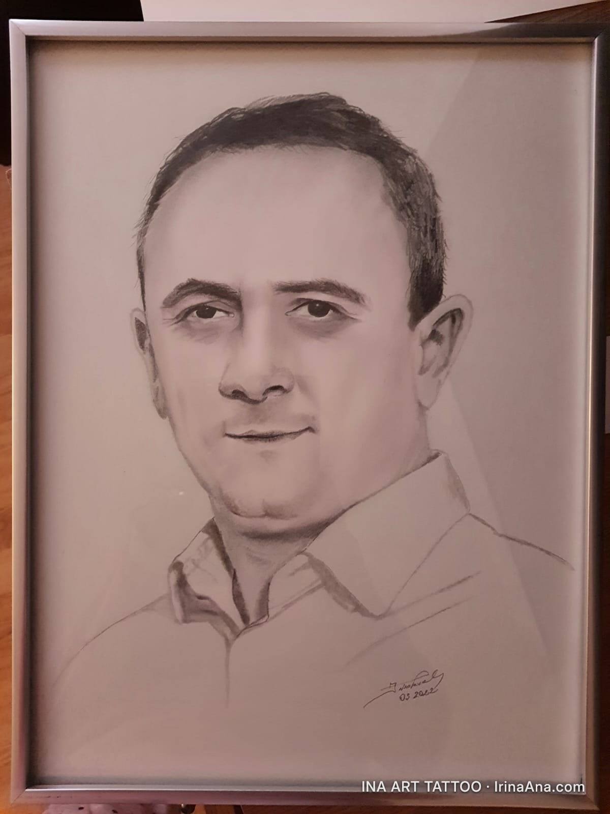 Portret în creion al unui bărbat chel, cu o cămașă deschisă la gât, înrămat.