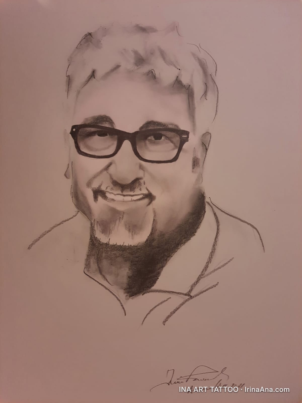 Portret în creion al unui bărbat zâmbitor, cu ochelari și barbă scurtă, pe un fundal deschis.